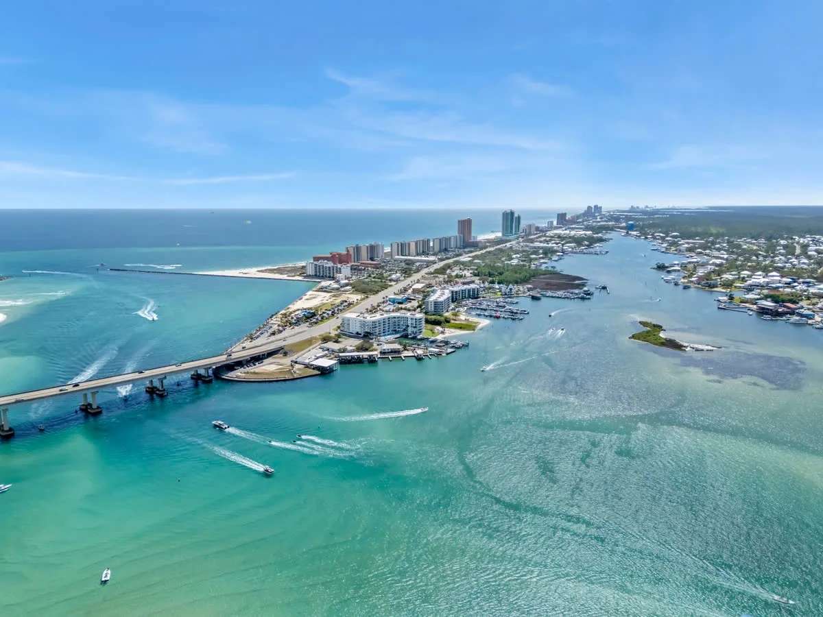 Aerial view of a waterfront coastal neighborhood, bridge, and turquoise water